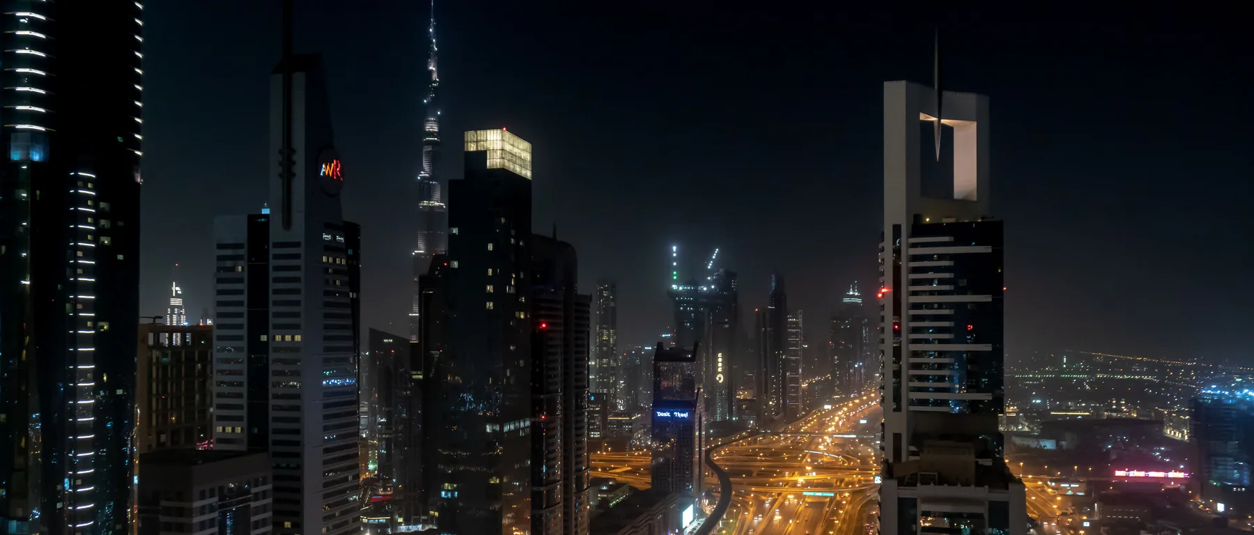 Sheikh Zayed Road at night with the lit towers of Downtown Dubai and the Burj Khalifa in the distance